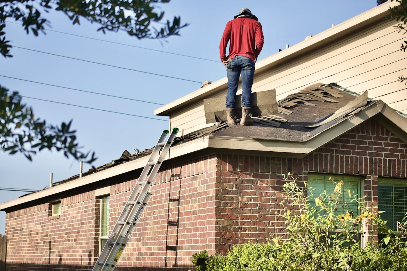 A roofer standing on a residential roof during a tear-off