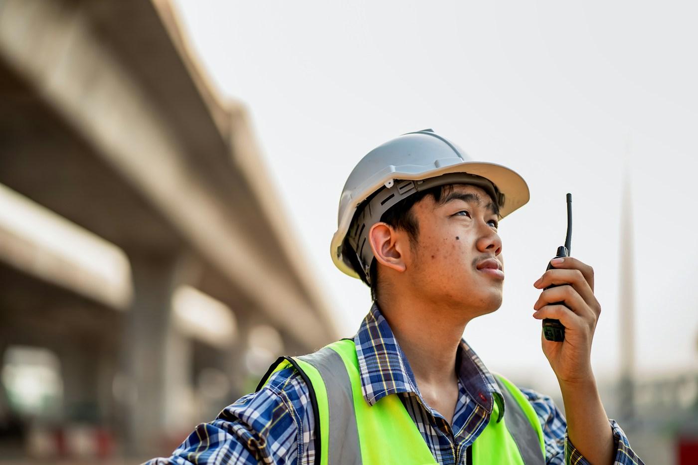 A site lead in a hard hat talking on a two-way radio